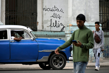 Des Cubains marchent devant le graffiti "Necesitas ser feliz" (Tu dois être heureux) du graffeur cubain Mr. Sad, à La Havane, le 12 décembre 2024 Des Cubains marchent devant le graffiti "Necesitas ser feliz" (Tu dois être heureux) du graffeur cubain Mr. Sad, à La Havane, le 12 décembre 2024
