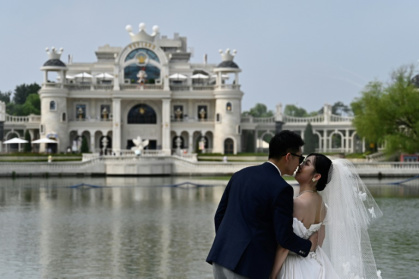 Un couple de mariés pose pour des photos au parc Chaoyang à Pékin, le 21 juillet 2024 Un couple de mariés pose pour des photos au parc Chaoyang à Pékin, le 21 juillet 2024