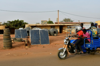 Une moto-taxi passe devant des panneaux solaires en vente dans une rue de Niamey, le 3 avril 2025 Une moto-taxi passe devant des panneaux solaires en vente dans une rue de Niamey, le 3 avril 2025