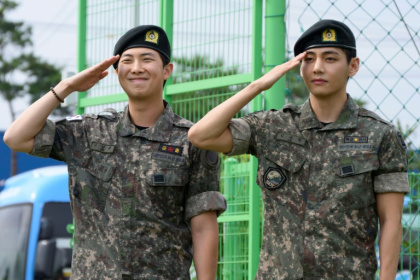 Les membres du boys band K-pop BTS RM (g) et V font un salut militaire dans un centre sportif en plein air à Chuncheon, en Corée du Sud, après avoir été libérés de leur service obligatoire le 10 juin 2025 - Shin Yong-ju (AFP)