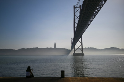 Une femme assise sur les bords du Tage près du pont du 25 avril dans le quartier touristique de Belem, à Lisbonne, le 19 novembre 2024 - PATRICIA DE MELO MOREIRA (AFP) Une femme assise sur les bords du Tage près du pont du 25 avril dans le quartier touristique de Belem, à Lisbonne, le 19 novembre 2024 - PATRICIA DE MELO MOREIRA (AFP)