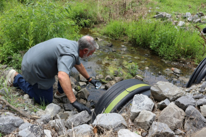 L'expert Bob Bowcock prelève des échantillons  d'eau pour évaluer la présence de polluants éternels (PFAS) dans un ruisseau d'une propriété à Dalton, dans l'Etat de Géorgie, aux Etats-Unis, le 12 juin 2025 - Issam AHMED (AFP)