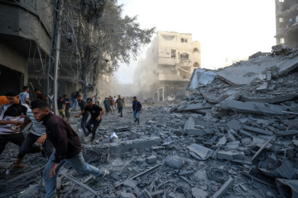 Des personnes courent se mettre à l'abri après une frappe israélienne qui a visé un bâtiment dans le camp de réfugiés palestiniens de Bureij, dans le centre de la bande de Gaza, le 19 octobre 2025 - Eyad BABA (AFP)