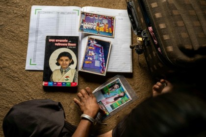 Ramati Mangla, qui a quitté l'école pour s'occuper de tâches ménagères, regarde ses anciennes photos et livres d'école dans sa maison du village de Bhadal, dans le district de Nandurba, le 25 septembre 2025 en Inde - Shefali RAFIQ (AFP)