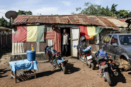 Un homme patiente à l'extérieur d'un café dans une banlieue populaire de la capitale guinéenne Conakry, le 26 septembre 2025 - PATRICK MEINHARDT (AFP)