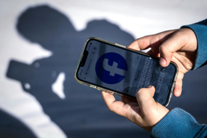 Un adolescent consulte Facebook sur son téléphone portable à Gosford, le 24 octobre 2025 en Australie - David GRAY (AFP)