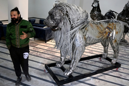 Le sculpteur Ehtisham Jadoon à côté de sa création, un lion à la crinière d'acier torsadé réalisé à partir de ferraille, dans son atelier situé à la périphérie d'Islamabad, le 29 décembre 2025 au Pakistan - Farooq NAEEM (AFP)
