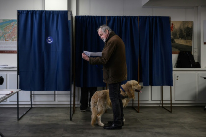 Un électeur et son chien devant un isoloir lors du premier tour des élections municipales, le 15 mars 2026 à Perpignan - Ed JONES (AFP)