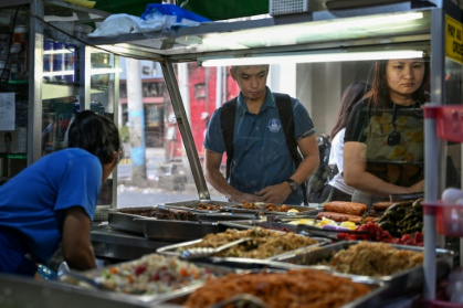 Des gens achetant de quoi manger dans une cantine de rue à Manille, le 7 avril 2026 - Jam STA ROSA (AFP)