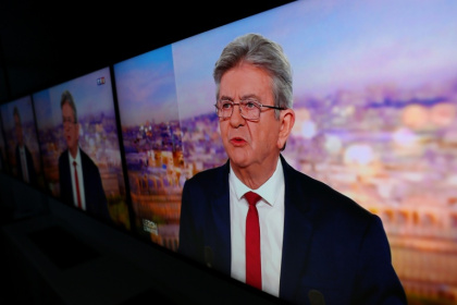 L'image du leader de LFI Jean-Luc Mélenchon affichée sur des écrans alors qu'il officialise sa candidature pour la présidentielle de 2027 sur le plateau de TF1, le 3 mai 2026 - Kiran RIDLEY (AFP)