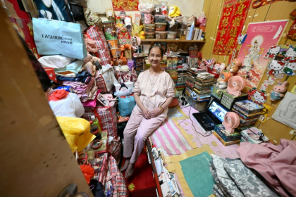 Lisa Lau assise sur son lit dans son logement d'un appartement subdivisé, le 30 avril 2026 à Hong Kong - Peter PARKS (AFP)