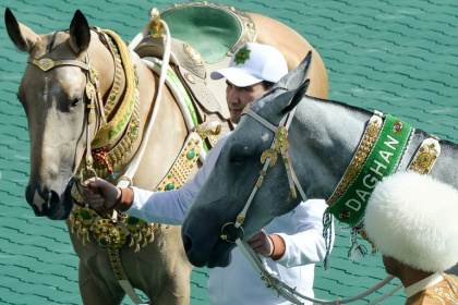 Le président turkmène Serdar Berdymoukhamedov et deux chevaux akhal-teke ,le 25 avril 2026 à Achkhabad - Natalia KOLESNIKOVA (AFP)
