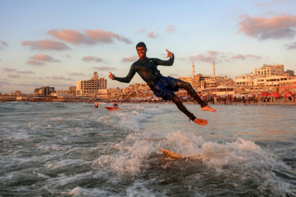 Un jeune Palestinien surfe au large d'une une plage de la ville de Gaza, le 21 juin 2026 - Omar AL-QATTAA (AFP)