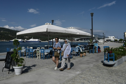 Des touristes venus de Turquie se promènent dans le village de Vathy, sur l’île de Samos, le 25 juillet 2026 - Sakis Mitrolidis (AFP)