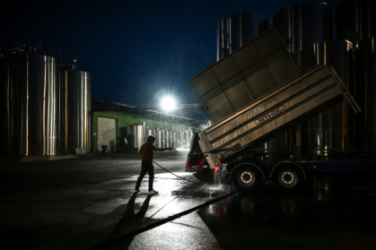 Avant que l'aube ne pointe, un employé nettoie une remorque durant la période des vendanges sur une propriété viticole à Val-de-Livenne, en Gironde, le 6 septembre 2023 - Philippe LOPEZ (AFP)