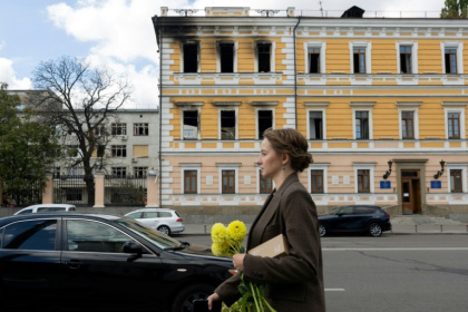 Une femme marche le 5 octobre 2026 devant le bâtiment de l'Académie nationale des sciences à Kiev endommagé par une frappe russe - Serhii Okunev (AFP)