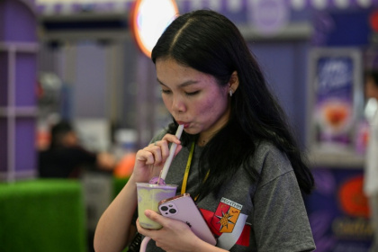 Une cliente boit une boisson à l'ube et au matcha dans un centre commercial de Quezon City, dans la métropole de Manille, le 23 septembre 2026 aux Philippines - Jam STA ROSA (AFP)